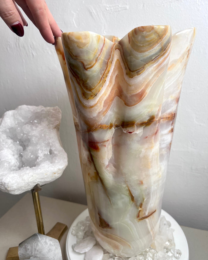 Decorative vase made from green onyx with marble-like pattern with a white background and additional decorative elements. 