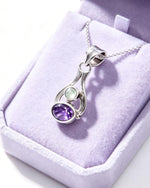 Silver pendant with gemstones on a purple velvet cushion
