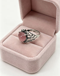 Silver ring with a pink stone in a pink jewelry box on a white background